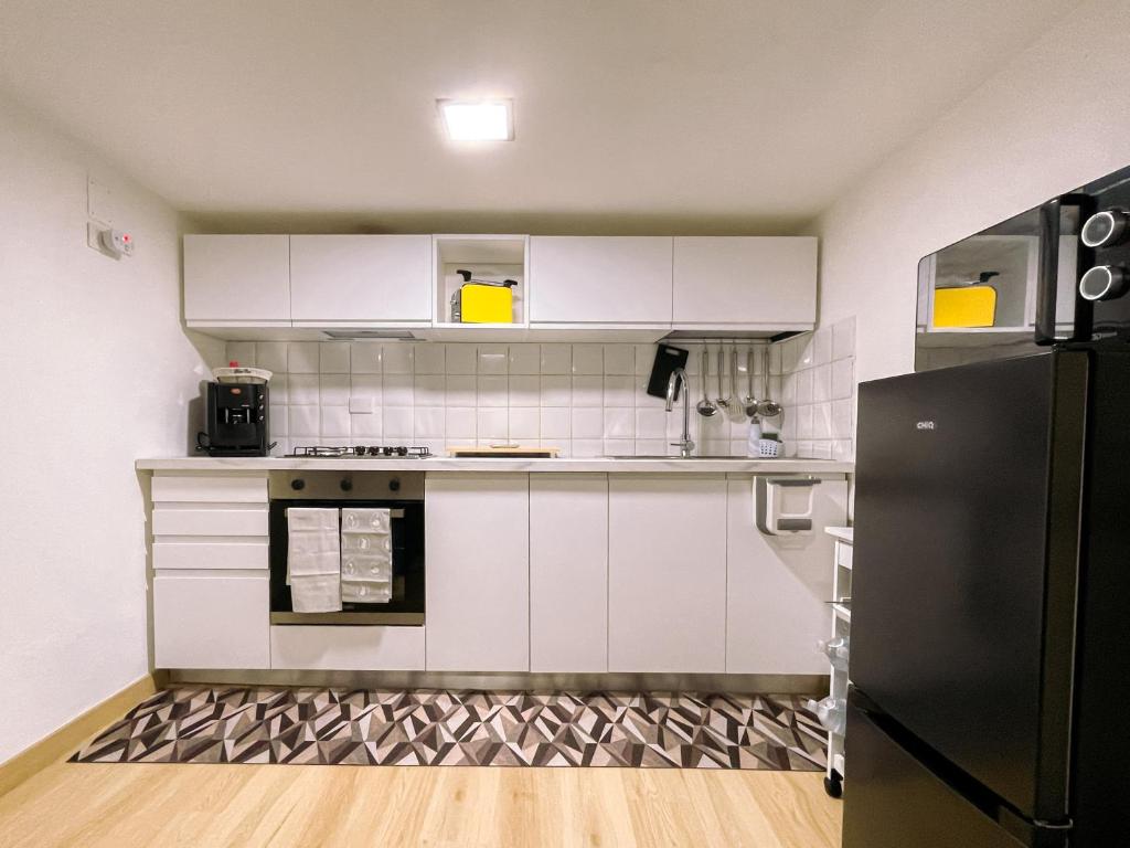eine Küche mit weißen Schränken und einem schwarzen Kühlschrank in der Unterkunft La Casetta di Giggè in Palermo