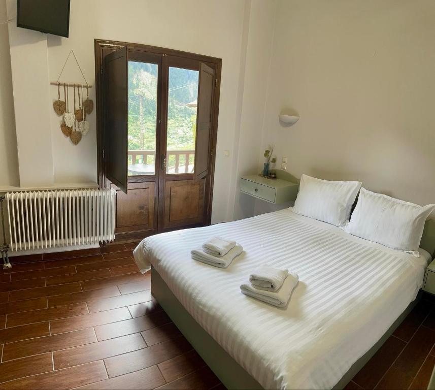 a bedroom with a large white bed with towels on it at Via Ferrata Hotel in Prousós