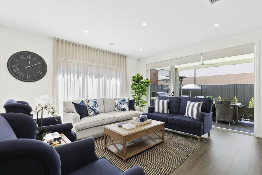 a living room with blue couches and a clock at Hampton's Getaway in Torquay in Torquay
