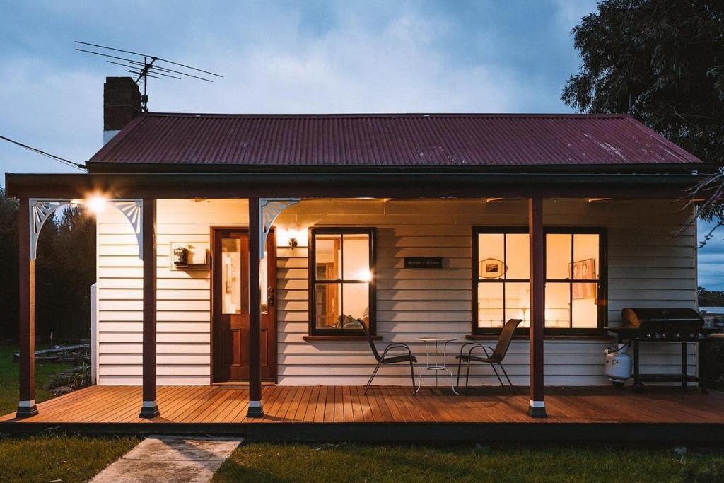 a small white house with a table and chairs on a deck at Sunset Cottage By The Bay Pet Friendly in Portarlington