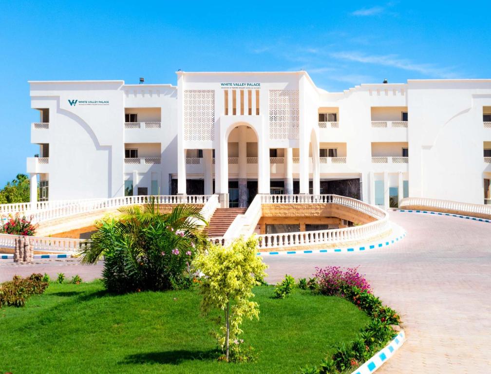 un gran edificio blanco con un jardín delante de él en White Valley Palace en Hurghada