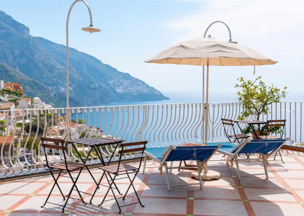 une terrasse avec une table, des chaises et un parasol dans l'établissement Florida Residence, à Positano