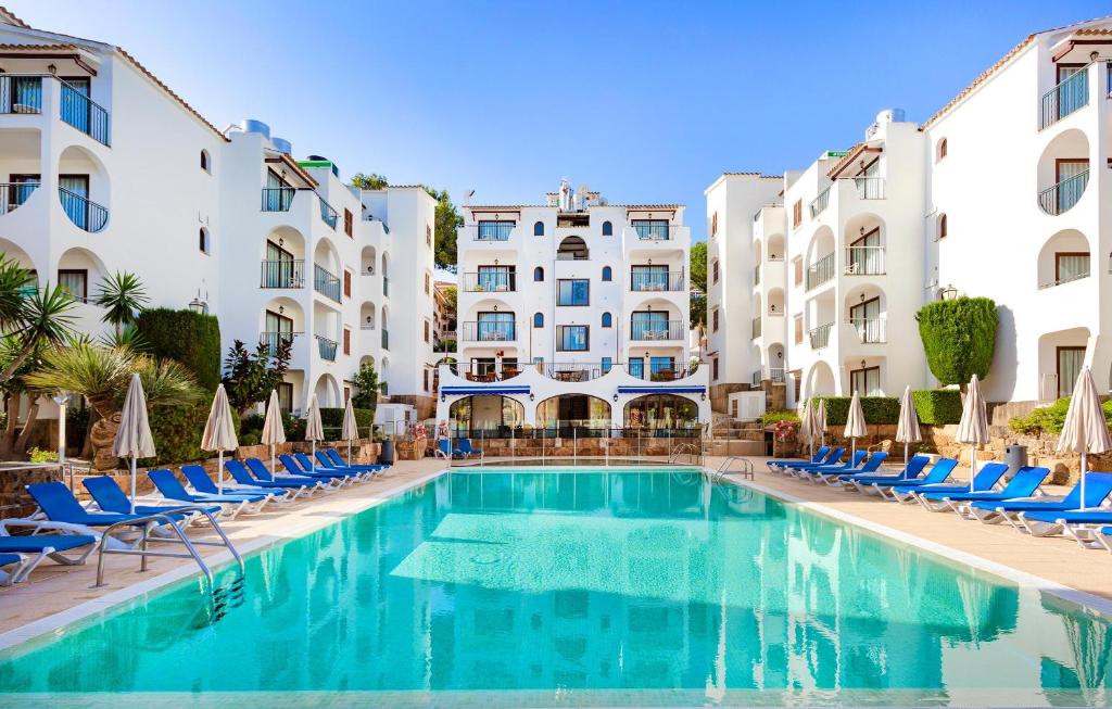 ein Pool in der Mitte eines Gebäudes mit Stühlen in der Unterkunft Flipflop Surfing Playa in Santa Ponsa