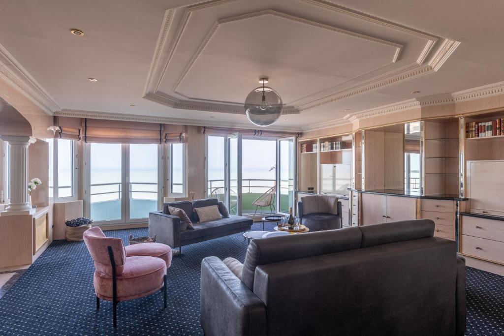 un salon avec un canapé, des chaises et des fenêtres dans l'établissement Le Navire - Appt vue mer à 50 m de la plage, à Mers-les-Bains