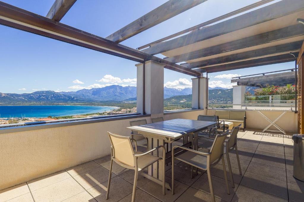 a table and chairs on a balcony with a view of the mountains at Les Aloes - Appt climatisé vue mer et montagne in Calvi