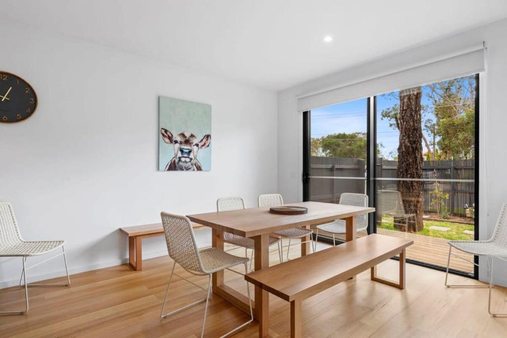 a dining room with a table and chairs and a clock at Sundrenched Barwon Heads in Barwon Heads