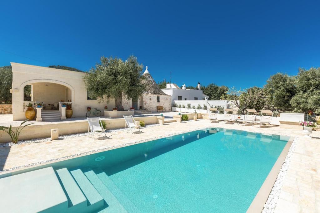 uma piscina com cadeiras e uma casa em Trulli Ulivo di Puglia by Perle di Puglia em Selva di Fasano