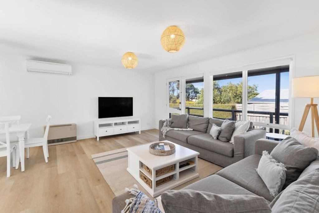 a living room with a couch and a tv at Blue Seas Beach House, 400 metres to the beach in Ocean Grove