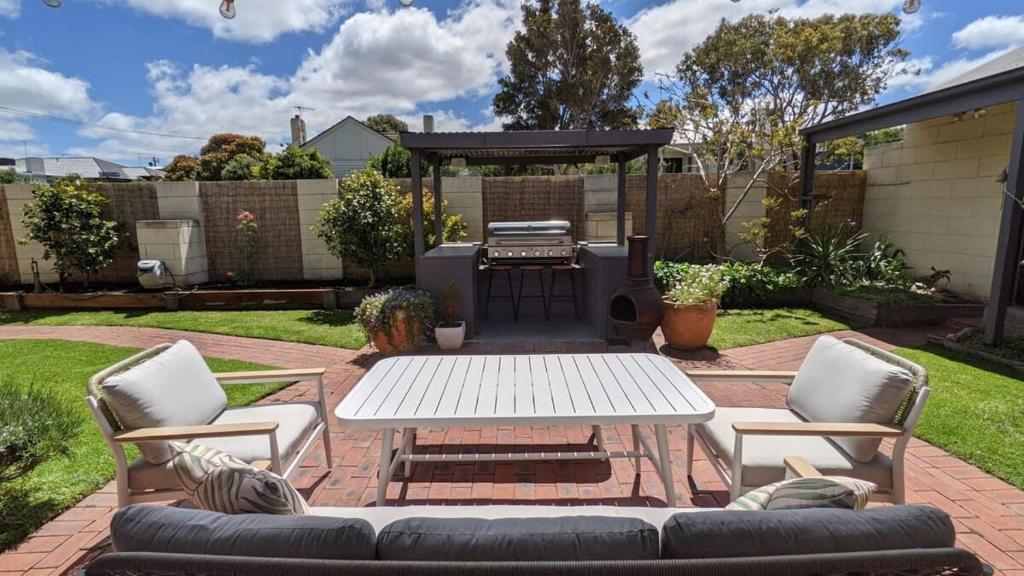 a patio with a white table and chairs and a grill at Coastal Serenity Central Torquay in Torquay