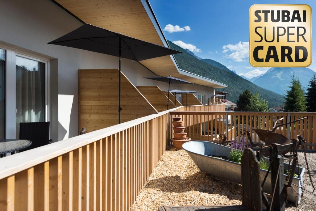 eine Veranda mit einer Badewanne und einem Sonnenschirm auf einer Terrasse in der Unterkunft An der Kaburga in Telfes im Stubai