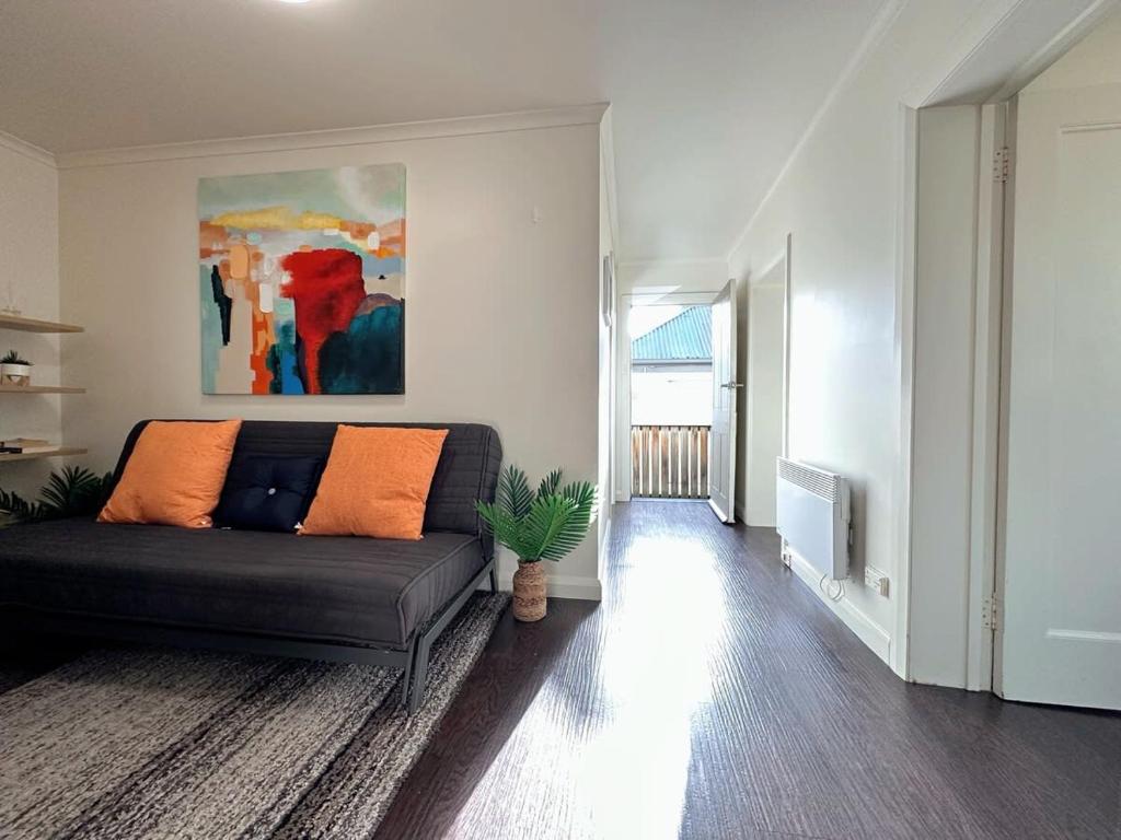 a living room with a black couch and a painting at Hobart City Oasis with 3 beds in Hobart