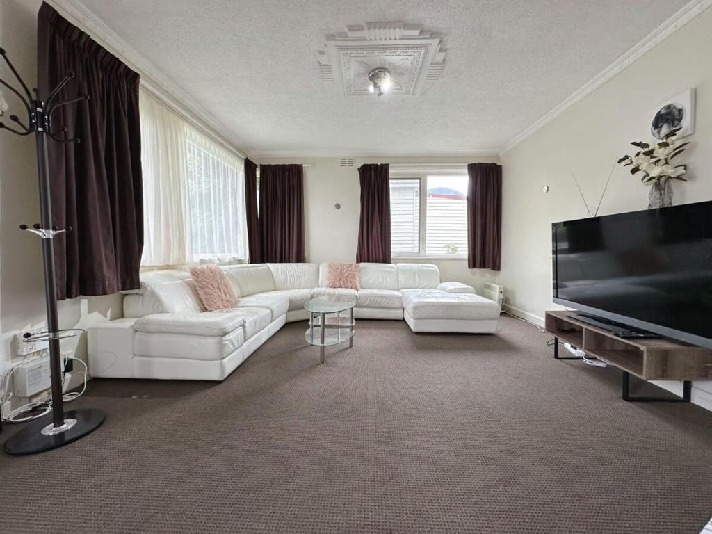 a living room with white furniture and a flat screen tv at Econo Lodge near Hobart City and Salamanca Market in Hobart