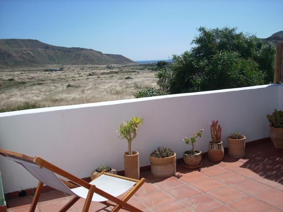 un balcón con una silla y macetas. en House in Rodalquilar valley en Rodalquilar
