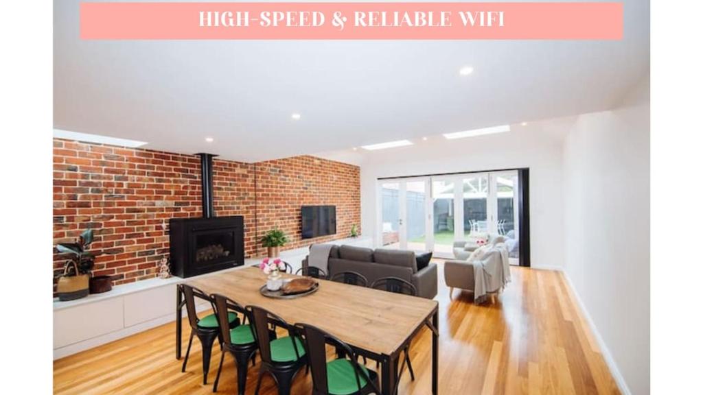 a living room with a table and chairs and a brick wall at SENSATIONAL Renovated Cottage in Beautiful Seddon in Seddon