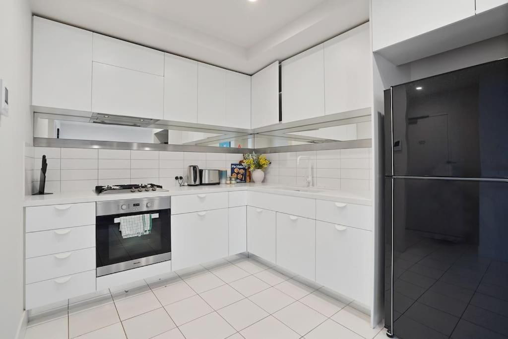 a white kitchen with a stove and a refrigerator at Lv53 Spanning 200 degrees with no obstacle view421 in Melbourne