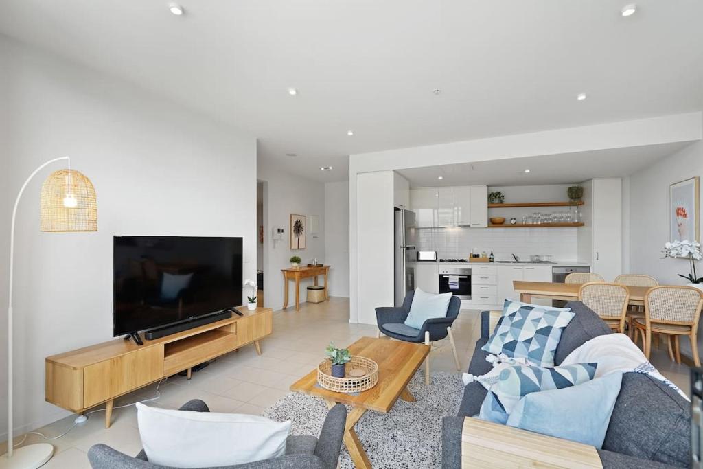 a living room with a couch and a tv and a table at A River-side 2bdm Footscray Oasis + Parking in Melbourne