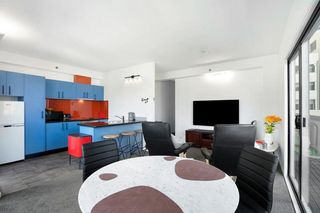 a living room with a table and a kitchen at Panoramic View CBD 1 Bed Apt +OFFICE (Collins) in Melbourne