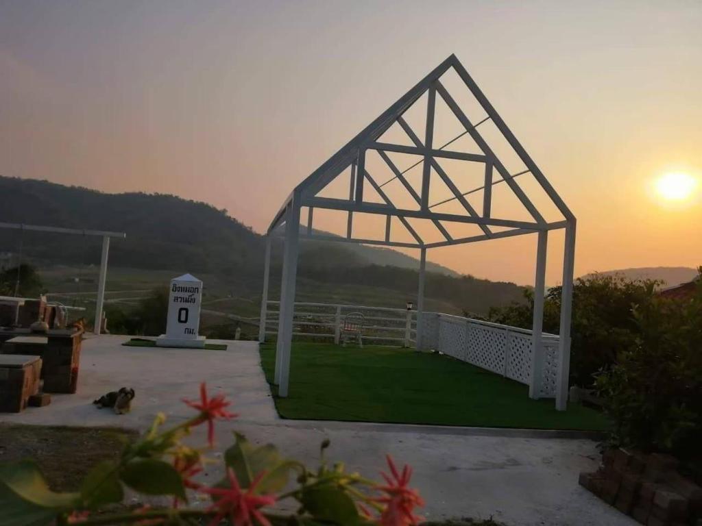 - un pavillon blanc avec le coucher de soleil en arrière-plan dans l'établissement Ingmhok Resort, à Suan Phueng