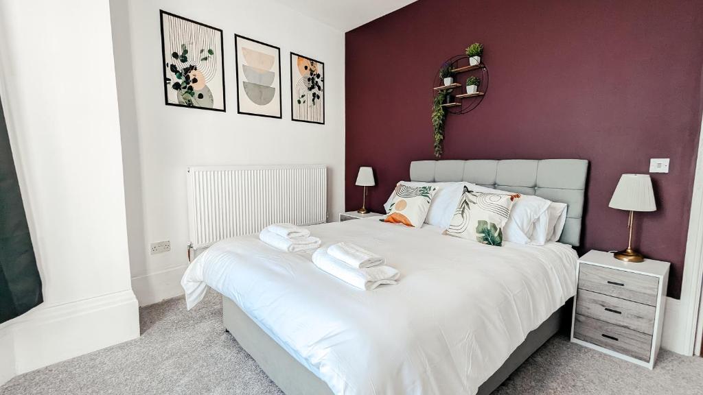 a bedroom with a white bed with purple walls at Eden Apartments in Bridlington
