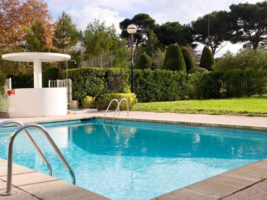 una piscina en un patio con árboles y arbustos en ibis Marseille Bonneveine Calanques Plages, en Marsella