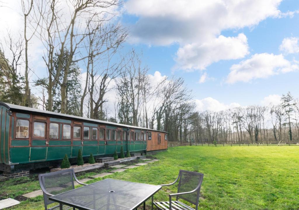 a green train sitting in a field next to a table at The Railway Carriage in Briston