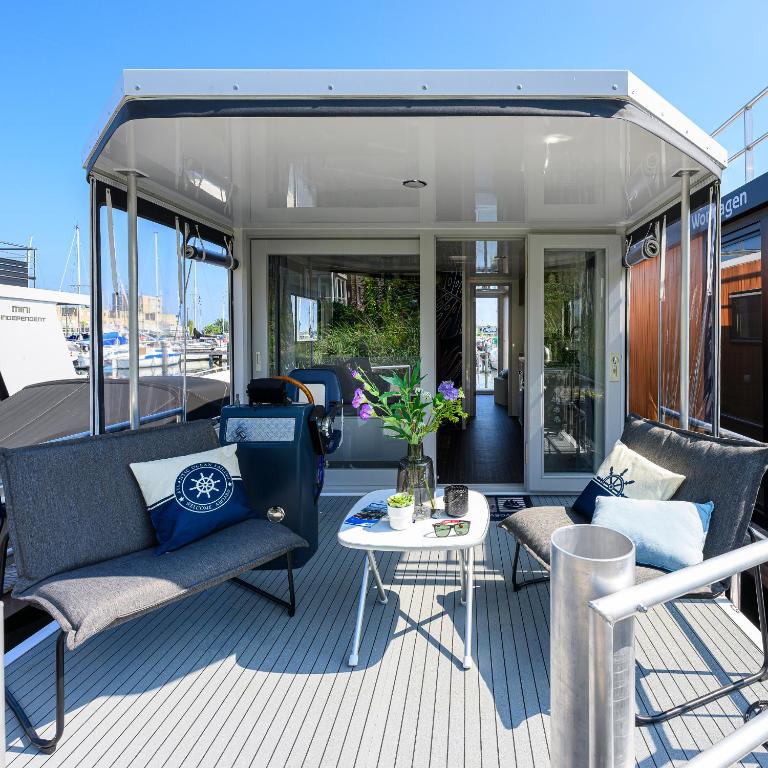 a deck of a boat with chairs and a table at Tiny Olav houseboat close to the beach and restaurants by Weltevreden Experience in Zeewolde