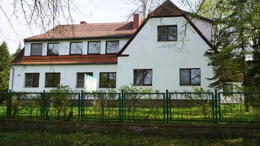 a white house with a green fence in front of it at Pensjonat Kowalski in Łubowo