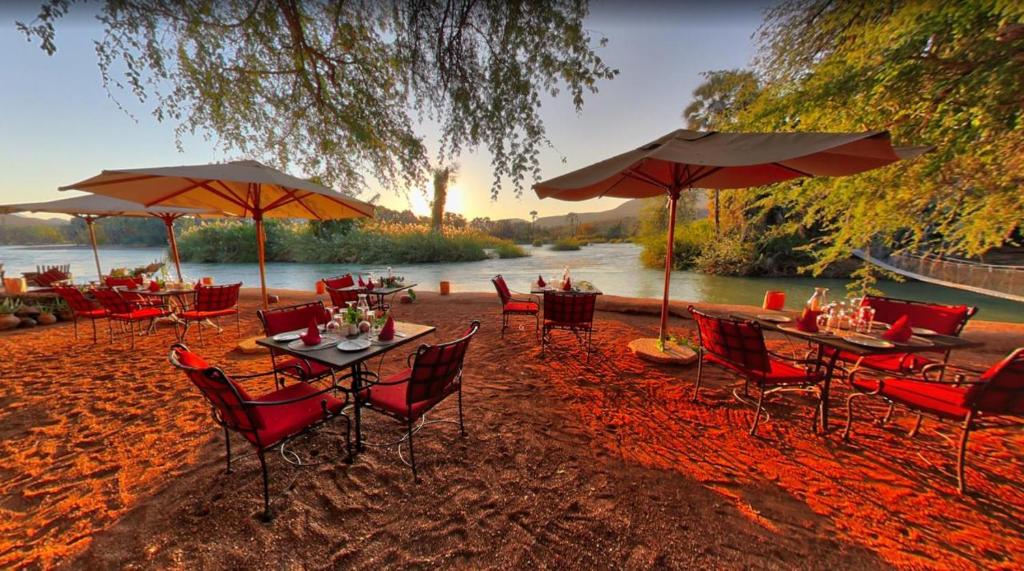 a group of tables and chairs with umbrellas on a beach at Epupa Camp in Epupa