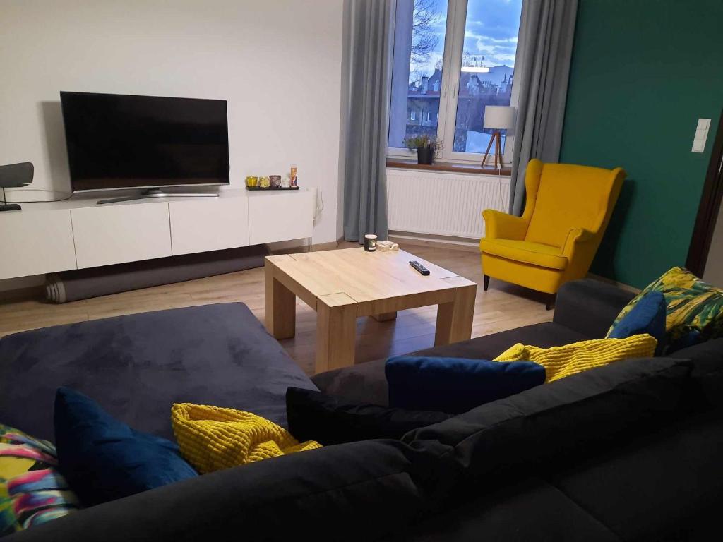 - un salon avec un canapé, une table et une télévision dans l'établissement Przestronne mieszkanie w centrum Chorzowa, à Chorzów
