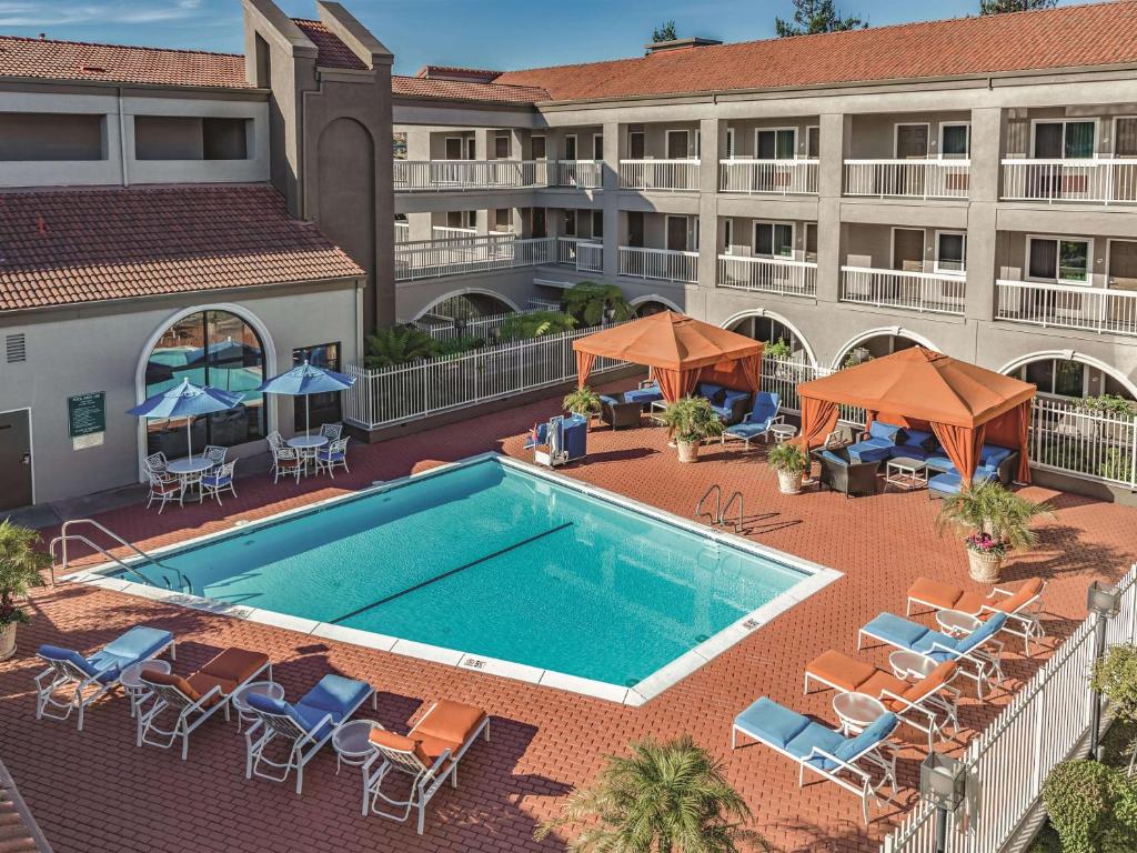 einen Luftblick auf einen Hotelpool mit Stühlen und Sonnenschirmen in der Unterkunft La Quinta by Wyndham San Francisco Airport West in Millbrae