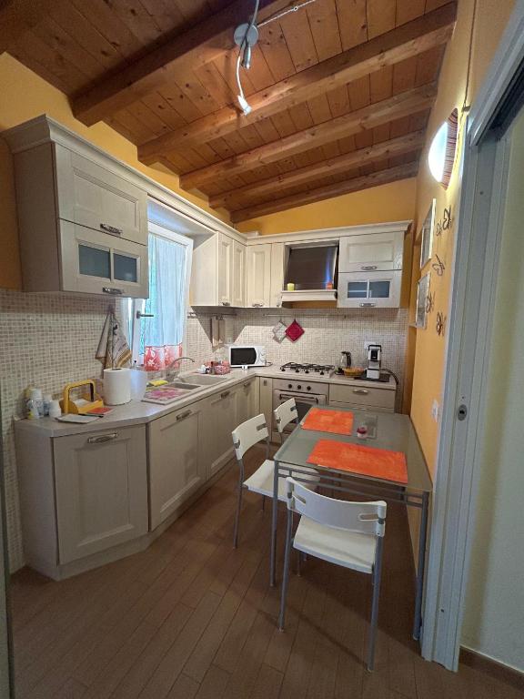 a kitchen with white cabinets and a table and chairs at La casina di Karol in Ronciglione