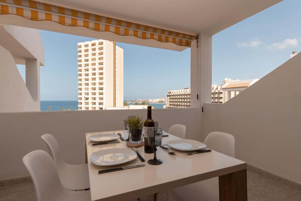a white table and chairs with a bottle of wine at Paloma Beach 10 - One Bed with sea view and wifi internet in Los Cristianos
