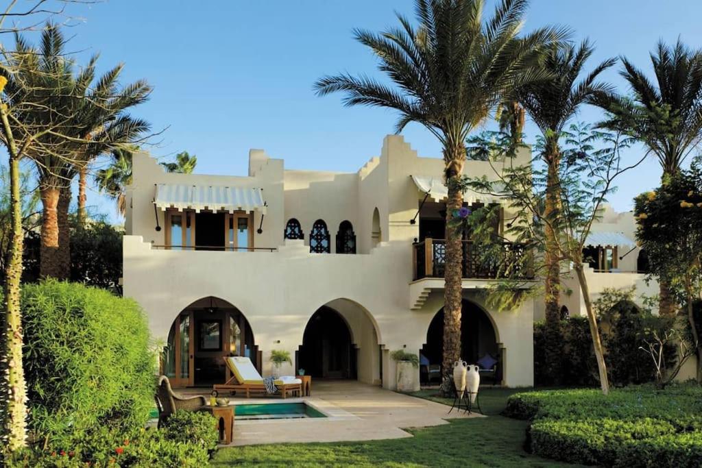 Beautiful villa at Four Seasons في شرم الشيخ: بيت ابيض كبير فيه نخل وساحة