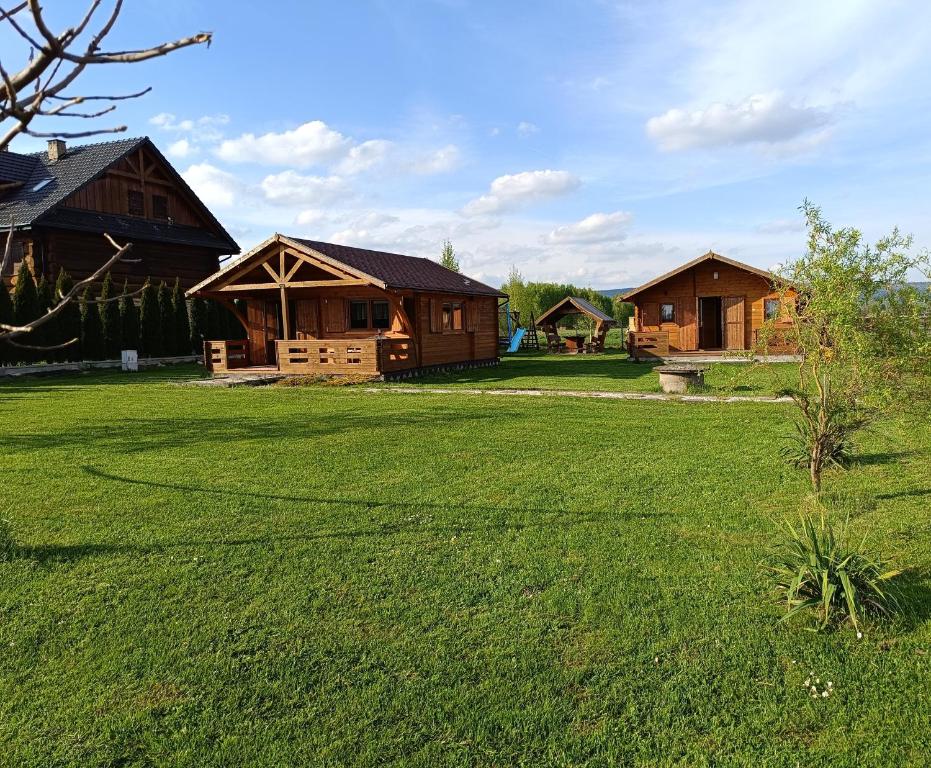 a yard with two log cabins in the background at Witówka in Bieliny