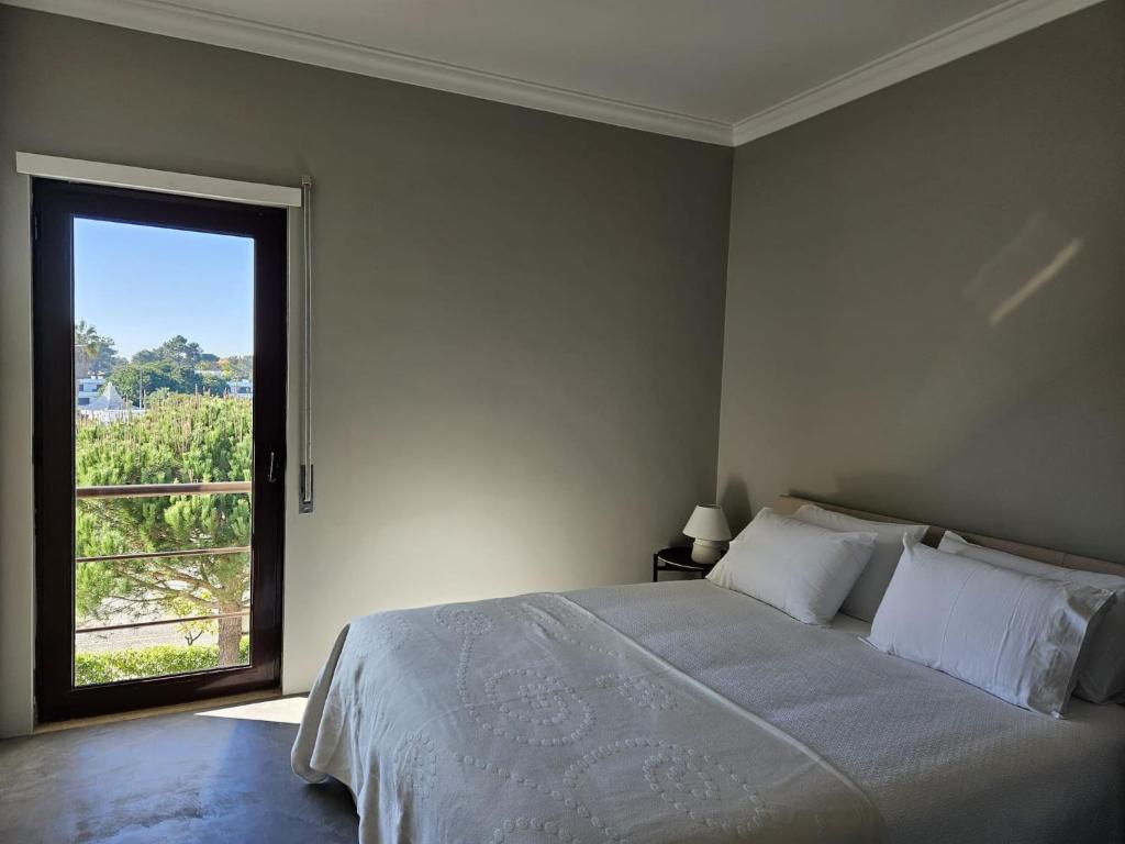 1 dormitorio con cama grande y ventana grande en Soltroia Beach River & Golf, en Grândola