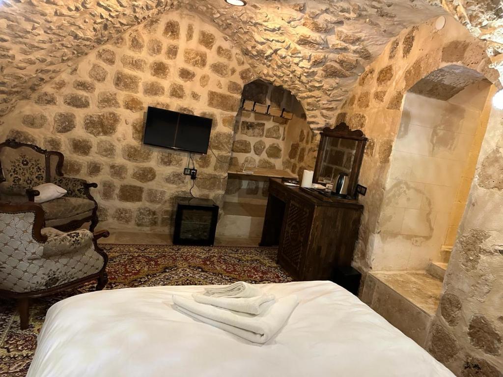 sypialnia z łóżkiem i telewizorem w budynku w obiekcie Rumet paşa konağı w mieście Mardin