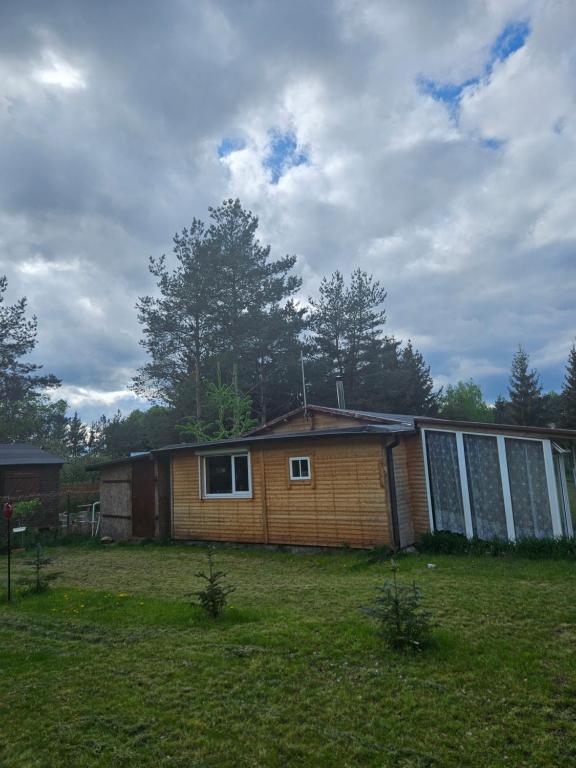 une petite maison dans un champ avec une cour dans l'établissement Domek letniskowy Zacisze, à Świętne