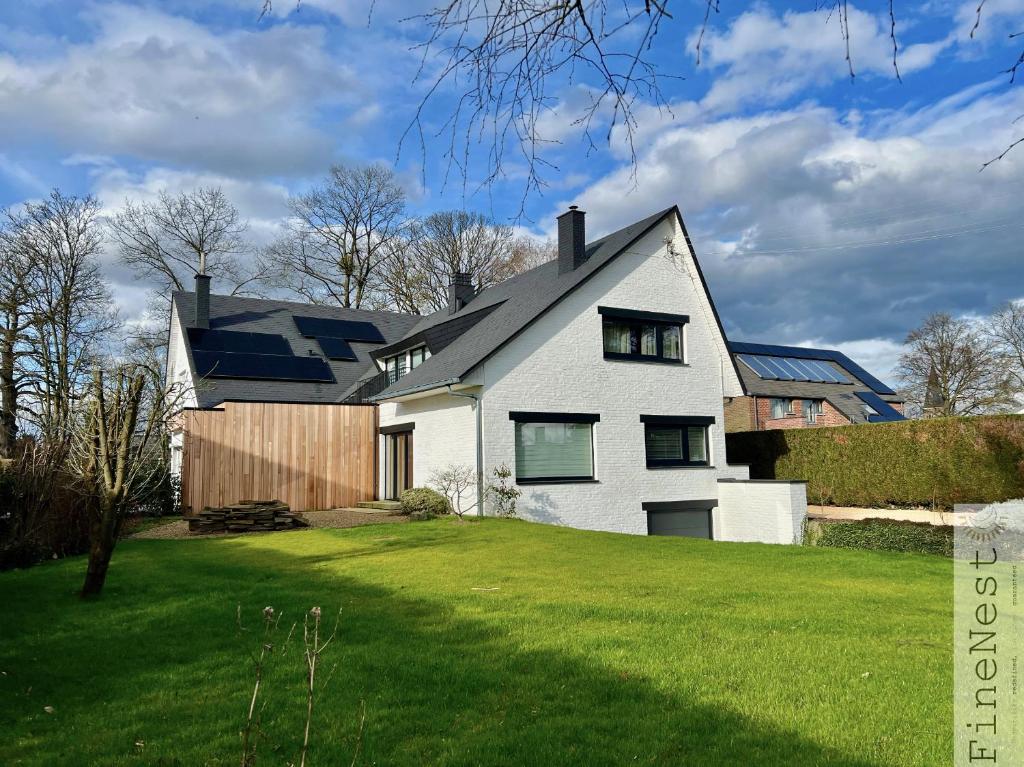 ein weißes Haus mit einem schwarzen Dach auf einem grünen Rasen in der Unterkunft Villa 3 chambres "La luxueuse Ardennes" by FineNest in Chaudfontaine