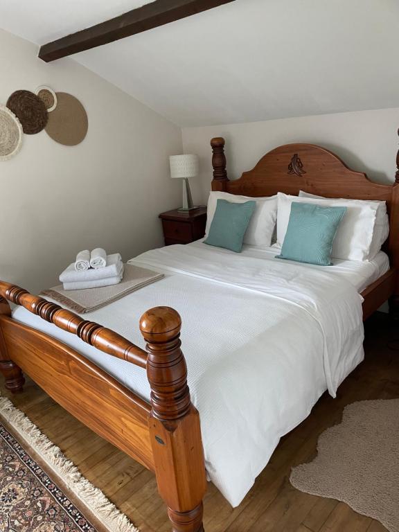 1 dormitorio con cama de madera con sábanas blancas y almohadas azules en Sunflowers, en Le Dorat