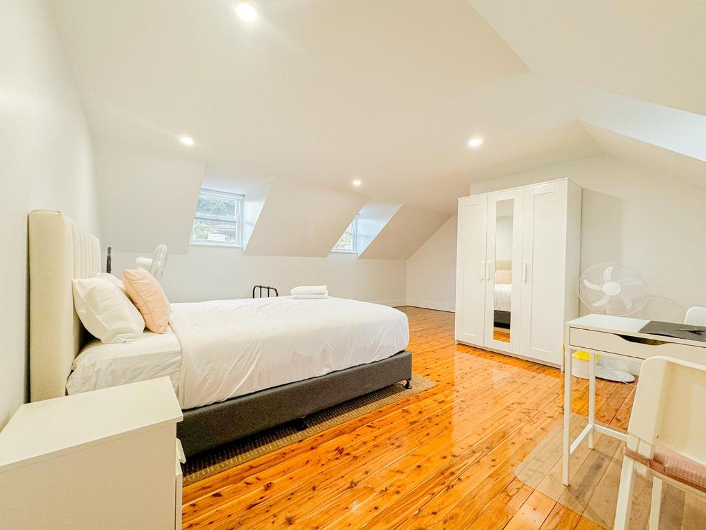 um quarto branco com uma cama e uma secretária em Kent Cosy House em Sydney