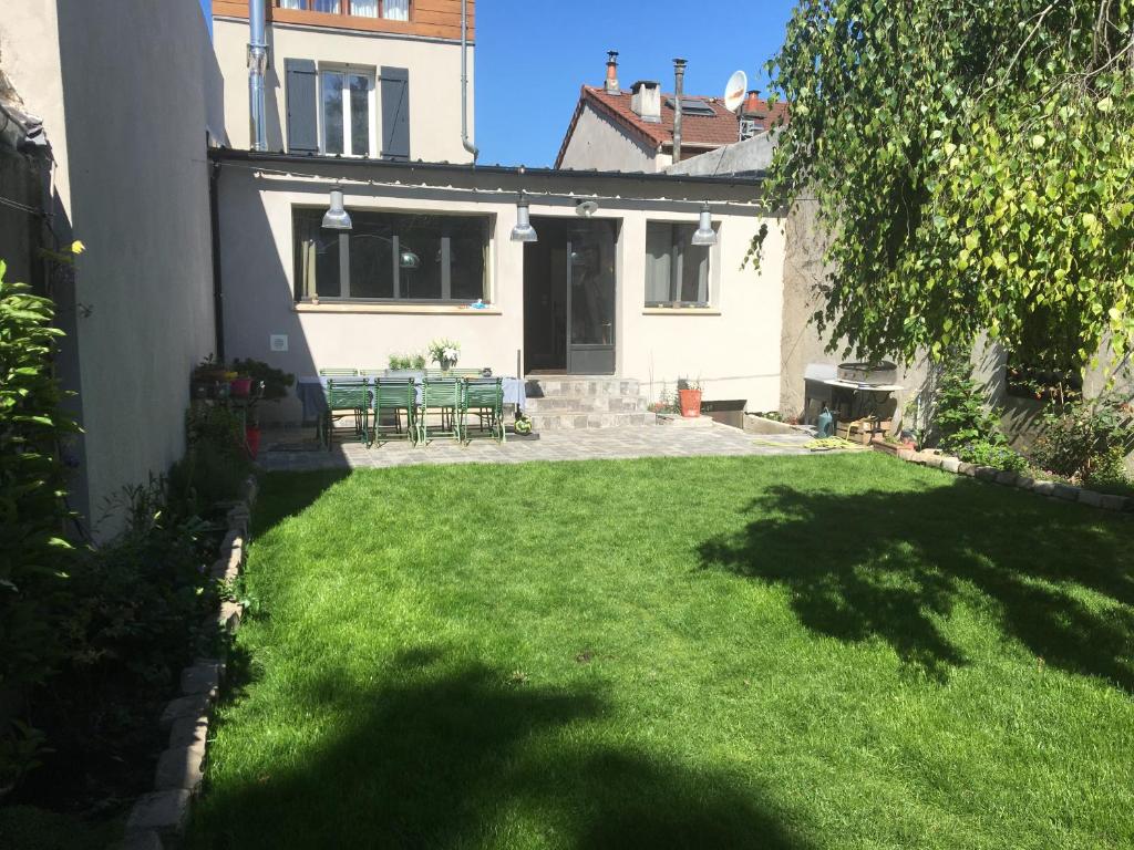 un patio con césped verde y una casa en Maison Saint Denis stade de France, en Saint-Denis