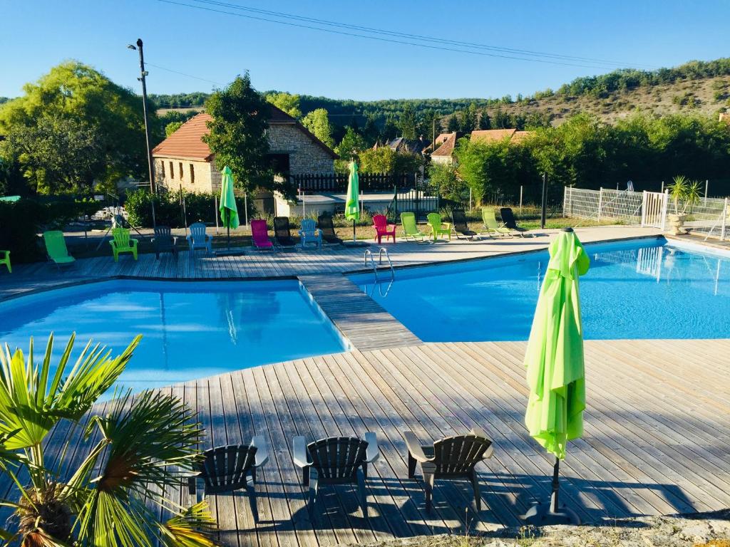 a swimming pool with chairs and a green umbrella at La Colline aux Chalets, Jaccuzi, Sauna in Saint-Chamarand