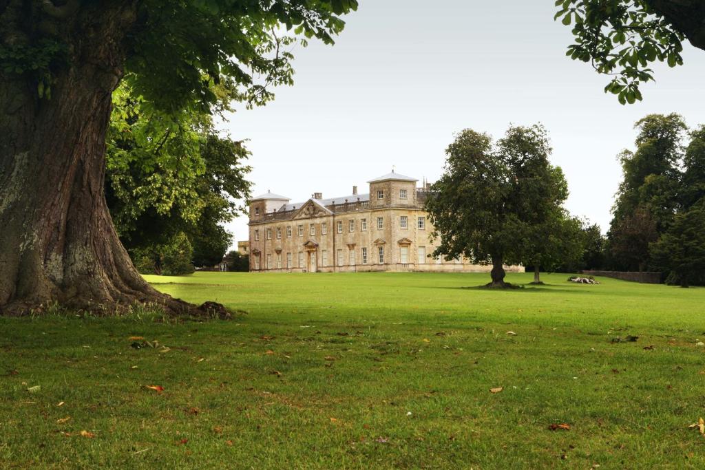 a large house in a field with a tree at Lydiard Park Hotel & Conference Centre in Swindon