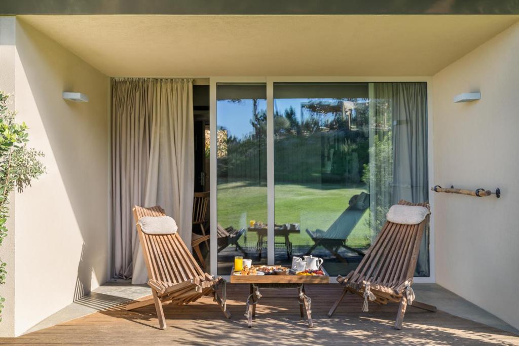 two chairs and a table in front of a glass door at Immerso Hotel, a Member of Design Hotels in Ericeira