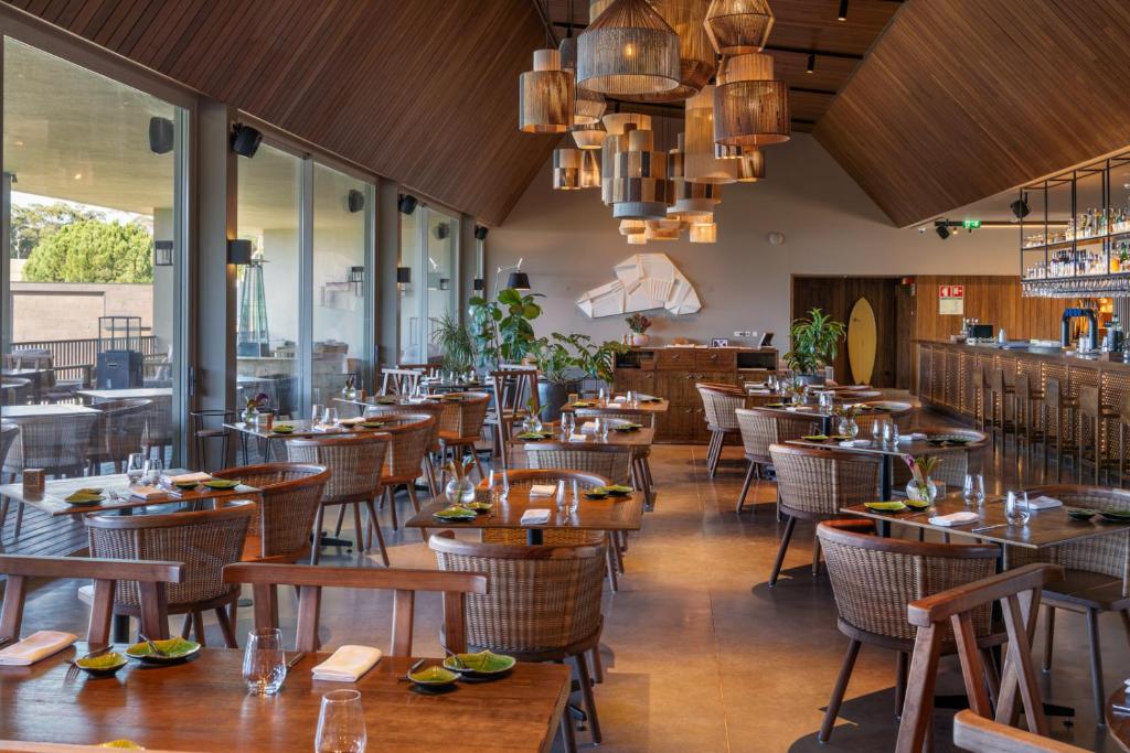 a restaurant with wooden tables and chairs and windows at Immerso Hotel, a Member of Design Hotels in Ericeira