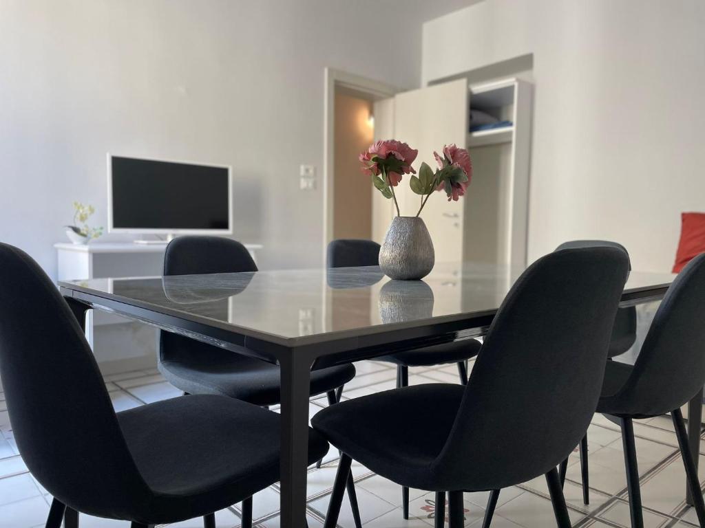 a dining room table with chairs and a vase with flowers at Dimora Vico Storella in Lecce