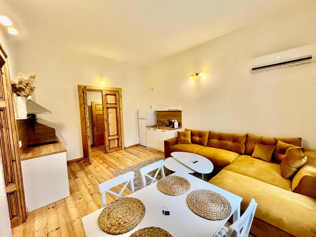 Una sala de estar con un sofá, una mesa y sillas. en SKYLER VINTAGE APARTMENTS, en Plovdiv