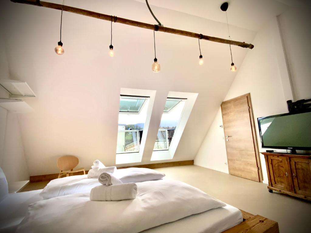 a bedroom with two white beds and a television at WATERFRONT - Urbane Eleganz am Bachufer in Villach