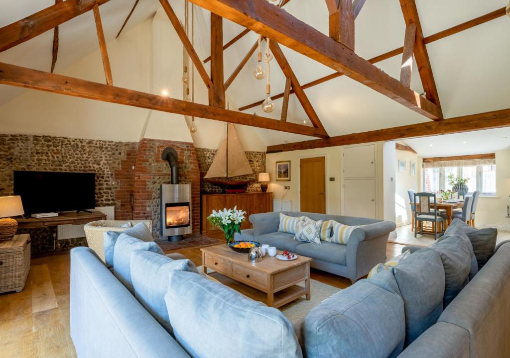 una gran sala de estar con sofás azules y chimenea en Boat Barn Cottage 6, en Blakeney