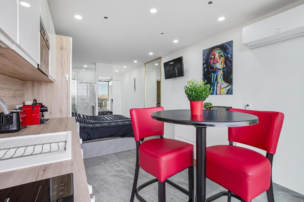 a kitchen and dining room with a table and red chairs at Héliopolis Naturist Luxury in Cap d'Agde